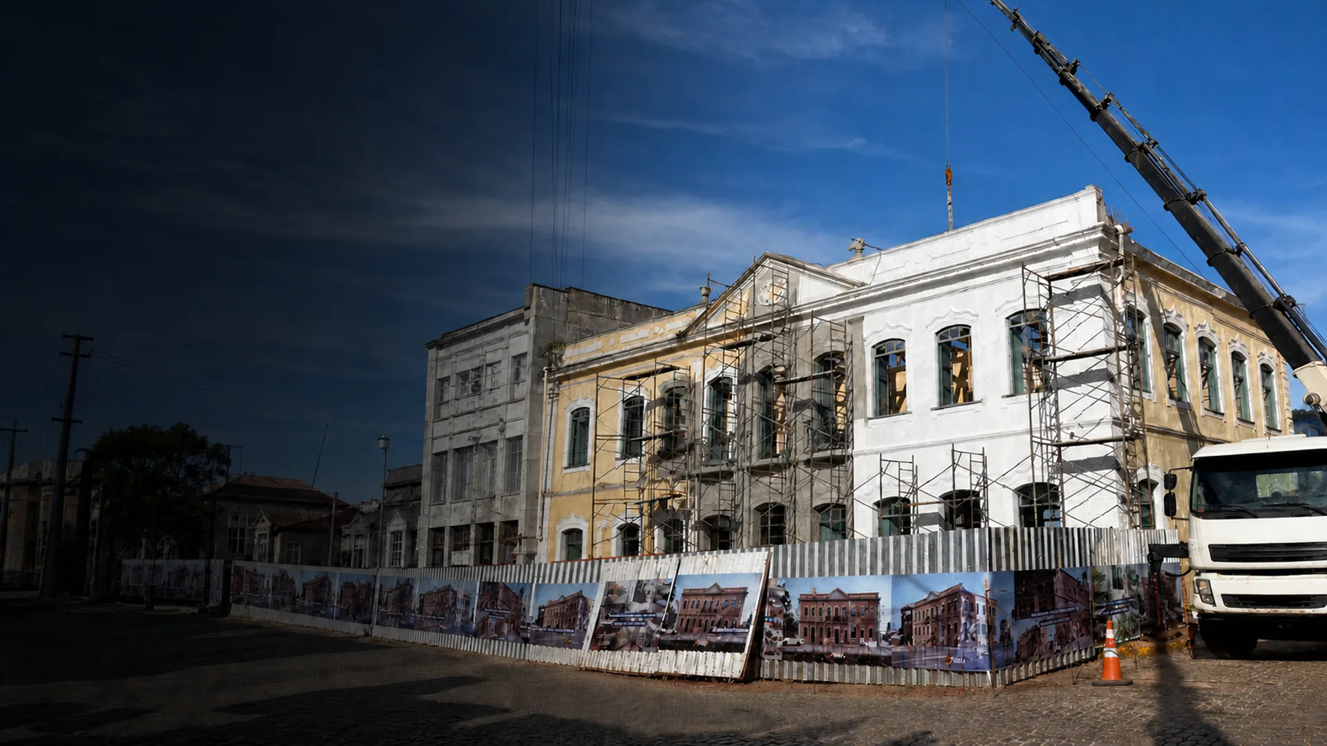 Restauro de prédio histórico em andamento, com fachada em recuperação, andaimes e guindaste posicionado na obra